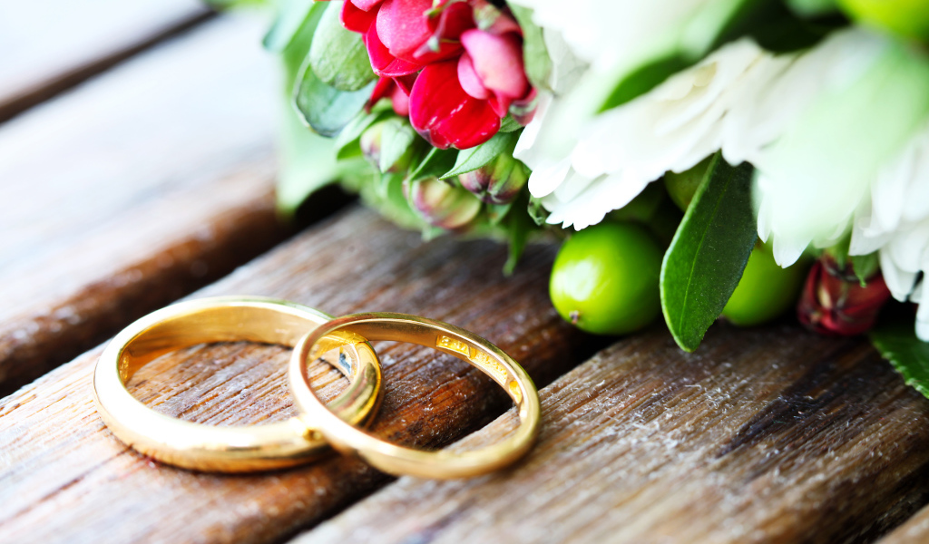 Два золотых обручальных кольца с букетом цветов