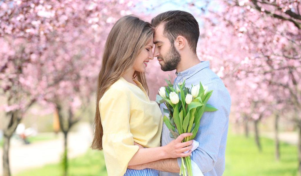 Влюбленная пара стоит в цветущем парке