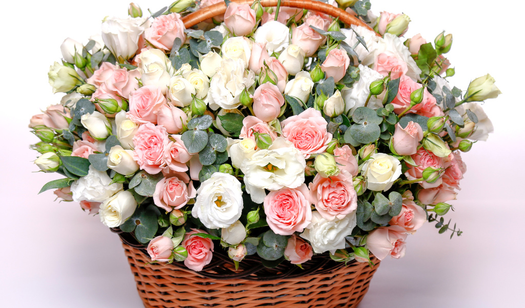 Basket with a beautiful bouquet of flowers roses, eustomams on a pink background