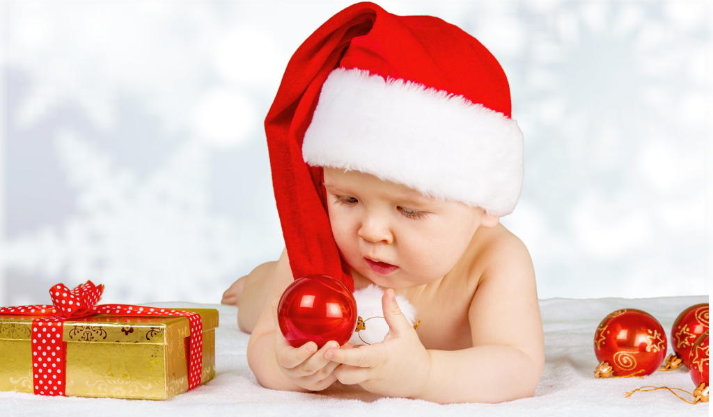 Младенец в красной новогодней шапке с елочными шарами на новый год