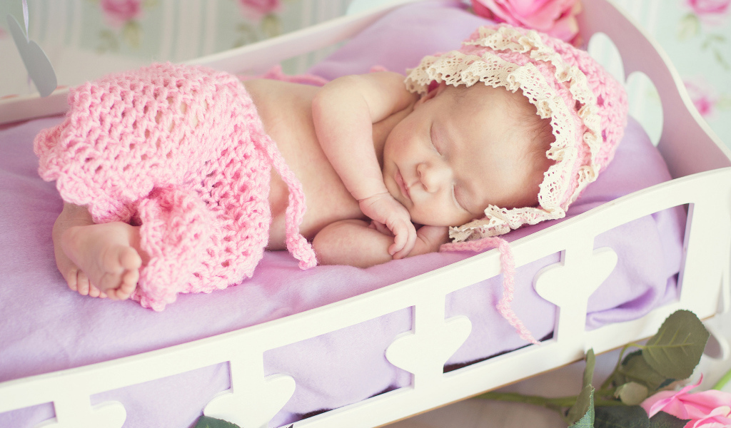 Спящий младенец девочка в розовом костюме в колыбели
