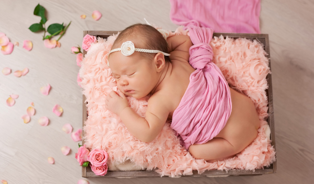 Спящий младенец с розовыми лепестками роз