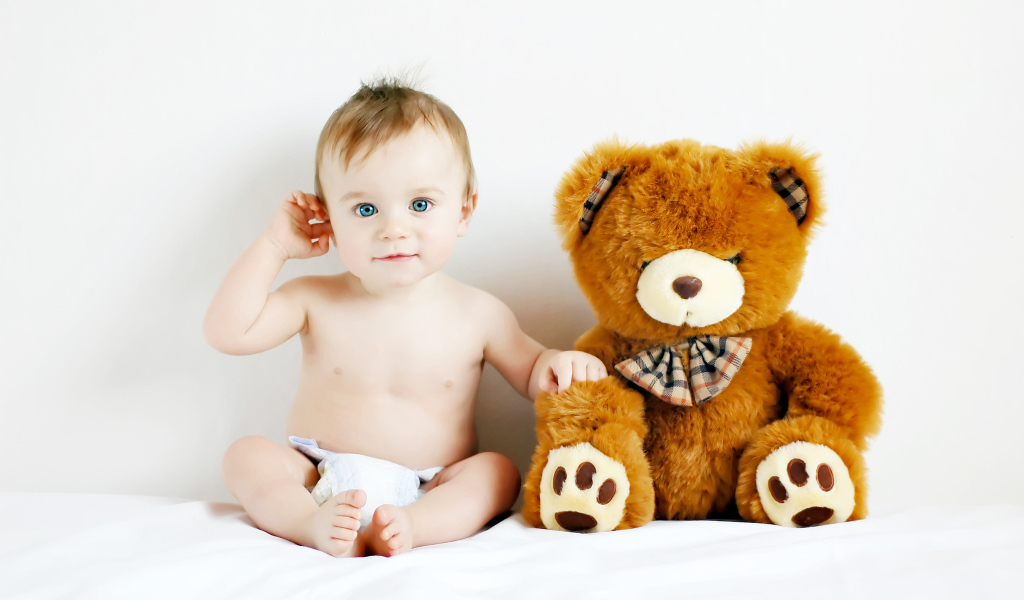 Маленький голубоглазый ребенок с большим плюшевым медведем