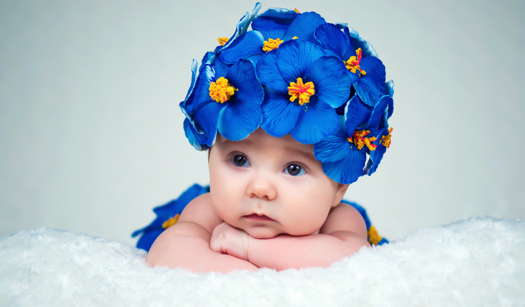 Маленький ребенок в красивой шапке с голубыми цветами