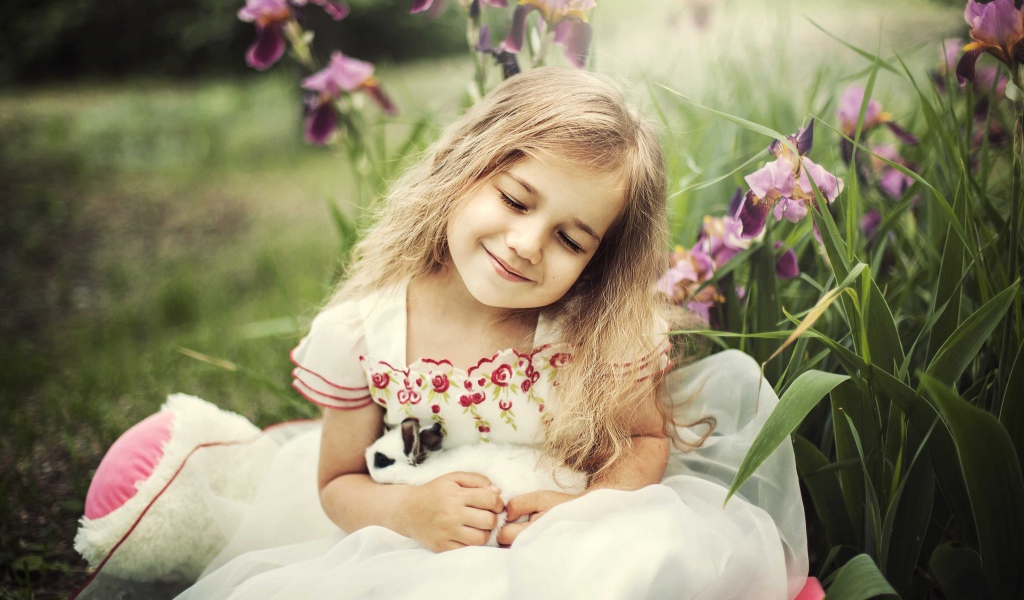 Маленькая девочка блондинка держит в руках кролика