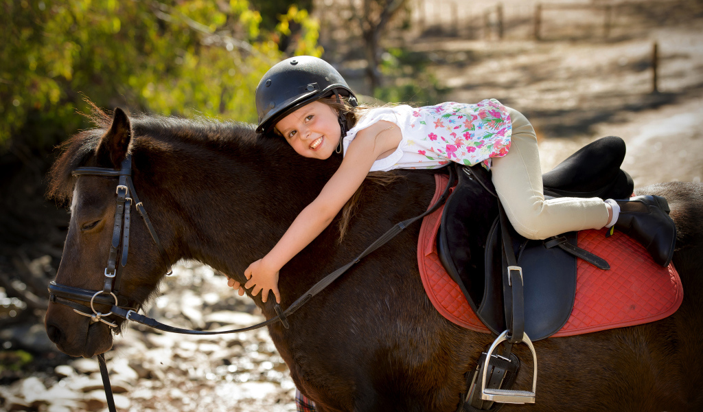 Маленькая девочка в шлеме верхом на пони