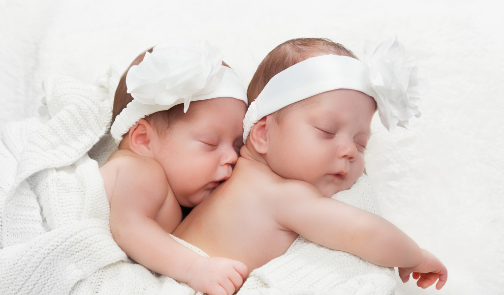 Два спящих младенца с большими белыми цветами на голове