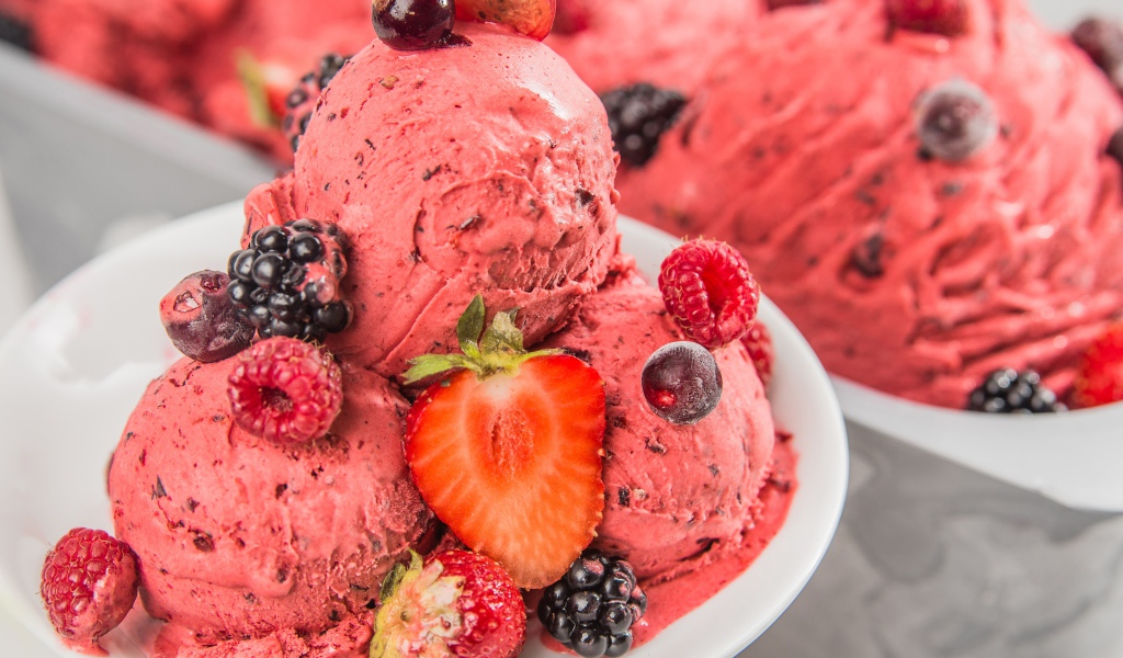 Шарики фруктового мороженого на тарелке с ягодами 