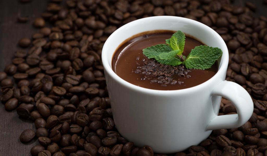 Белая чашка горячего шоколада стоит на кофейных зернах