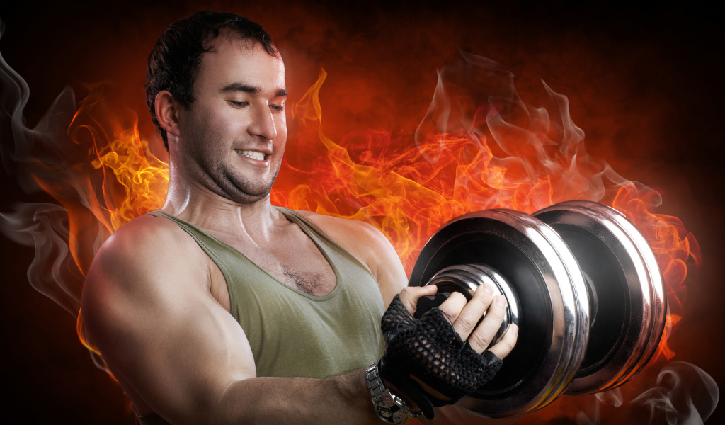 Мужчина спортсмен держит в руках гантелю на фоне огня