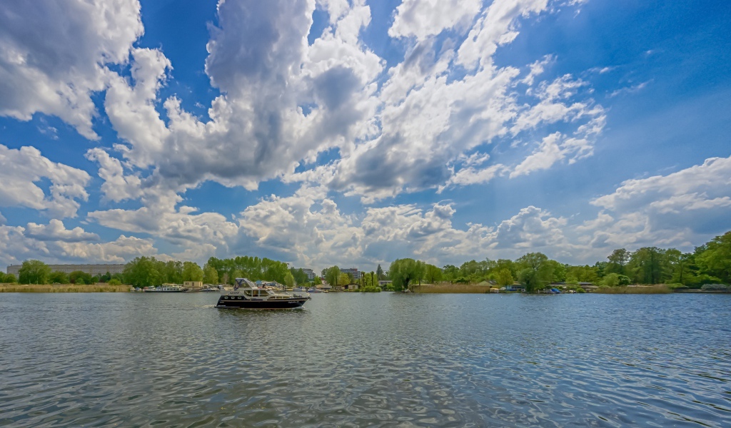 Катер на озере под красивым голубым небом с белыми облаками