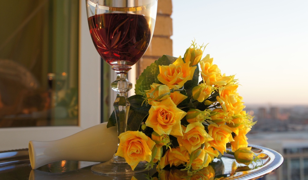 Букет желтых роз на столе с бокалом вина