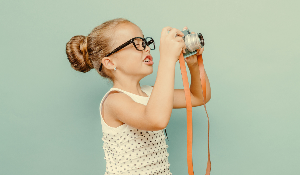 Маленькая девочка в очках с фотоаппаратом
