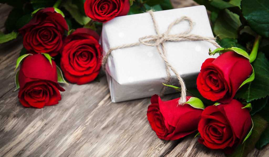 Букет красных роз на столе с подарком на 8 марта