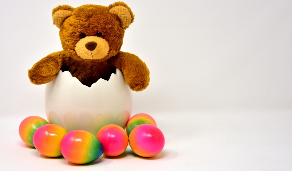 Медвежонок с яркими пасхальными яйцами на сером фоне
