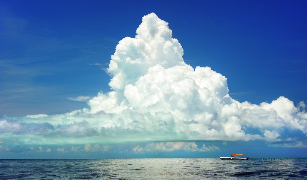 Большое белое облако в голубом небе над морем 
