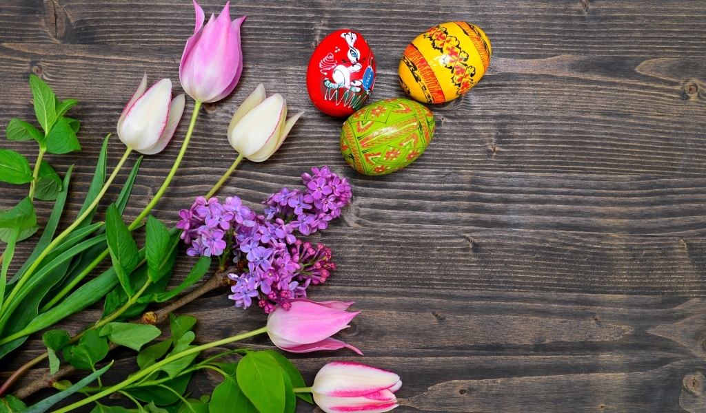 Пасхальные яйца с живыми цветами на столе 
