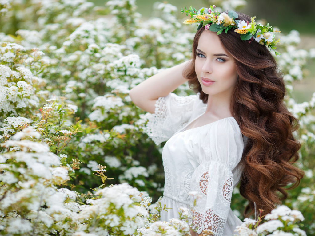 Нежная молодая девушка в белом платье с венком на голове