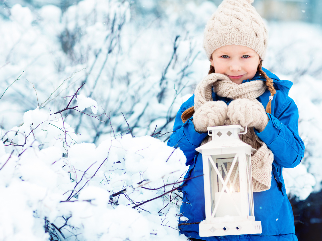 Маленькая девочка в синей куртке с фонарем  в руках зимой