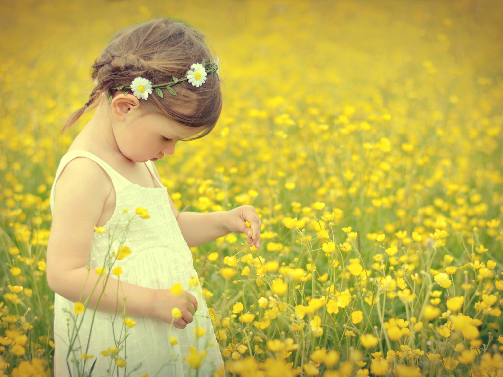 Маленькая девочка в белом платье на лугу с желтыми цветами