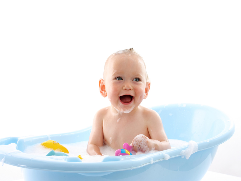 Smiling baby sitting in blue bath on white background