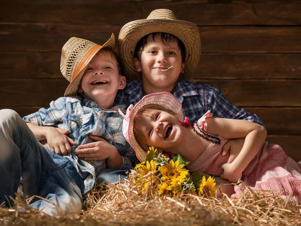 Два улыбающихся мальчика и девочка в соломенных  шляпах