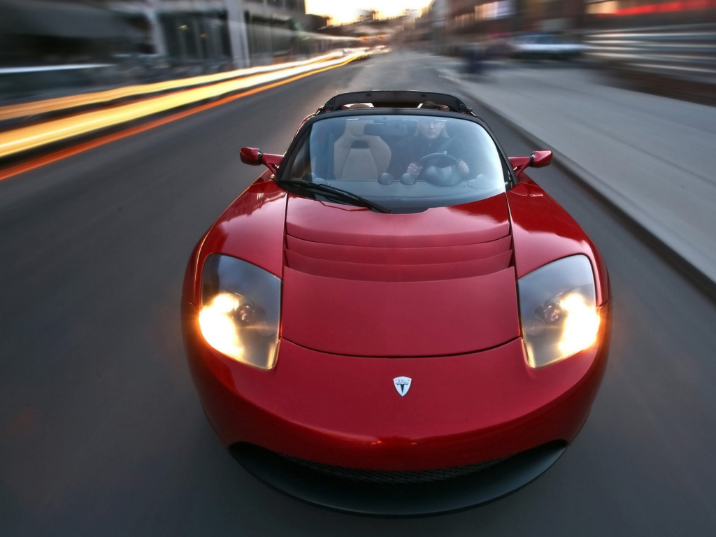 Красный электромобиль Tesla Roadster на трассе 