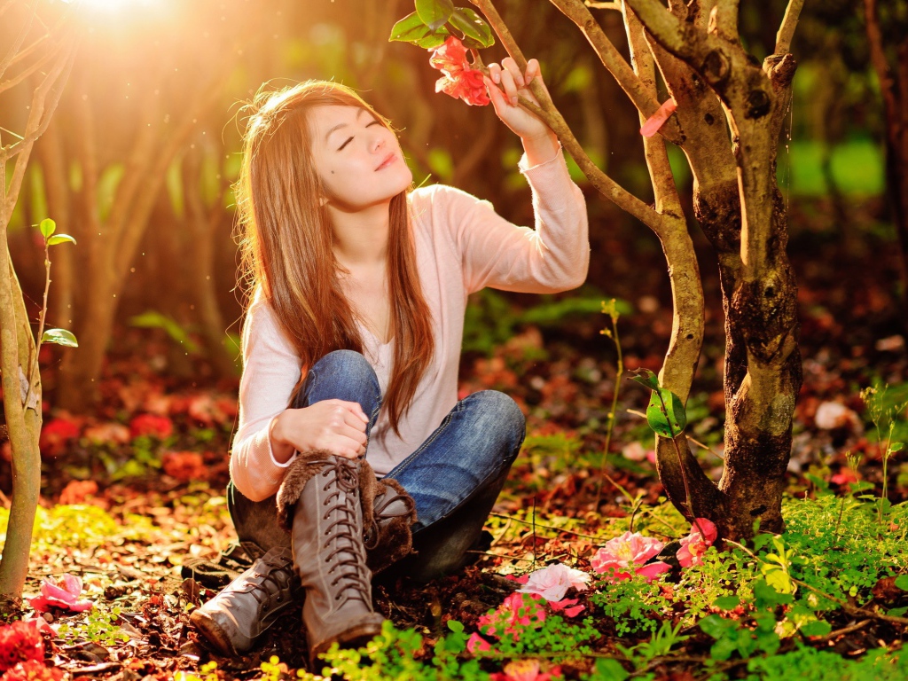 Девушка сидит на земле под ярким солнцем в лесу