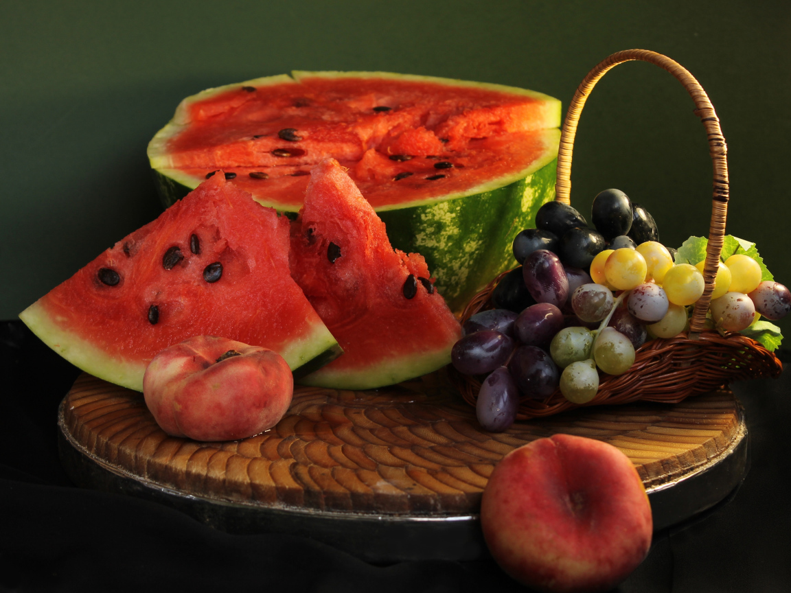 Нарезанный арбуз на столе с виноградом и персиками