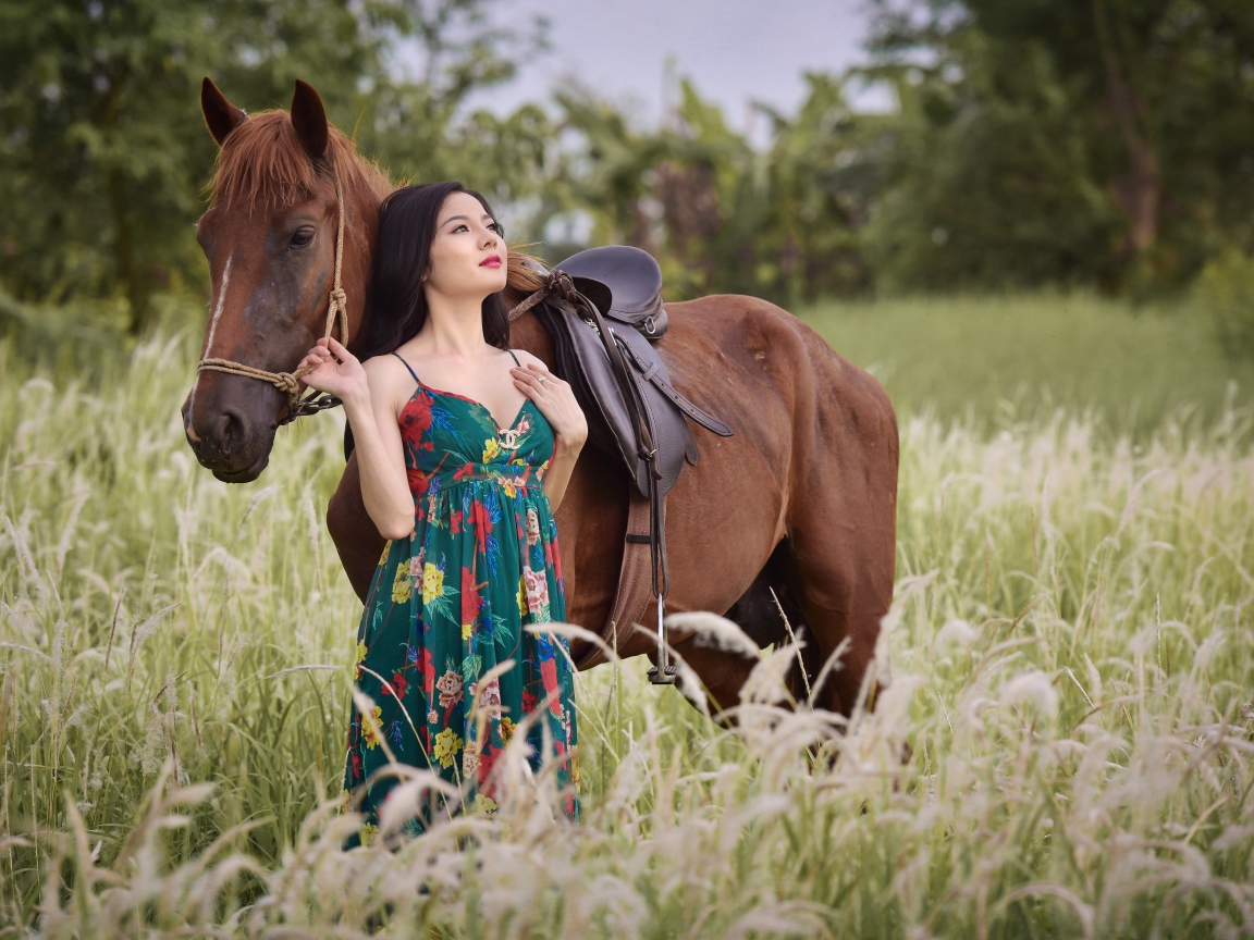 Красивая девушка азиатка с конем в поле