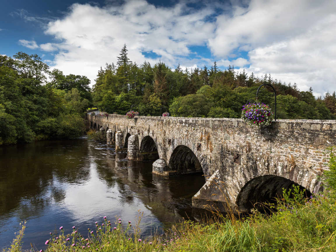 Мост через реку у леса на фоне красивого голубого неба с белыми облаками. Ирландия
