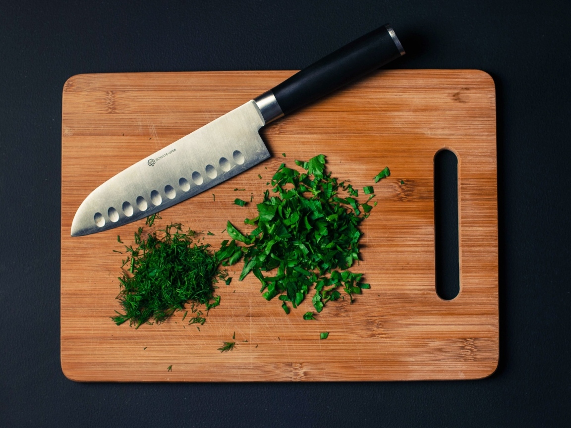 Нарезанная зелень на доске с ножом