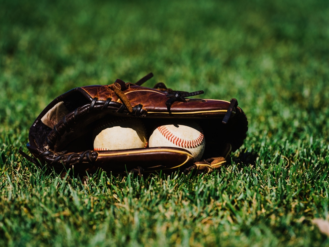 Бейсбольная перчатка и мячи на зеленой траве