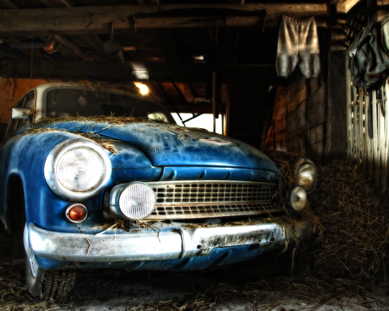 Старый автомобиль присыпан сеном в сарае