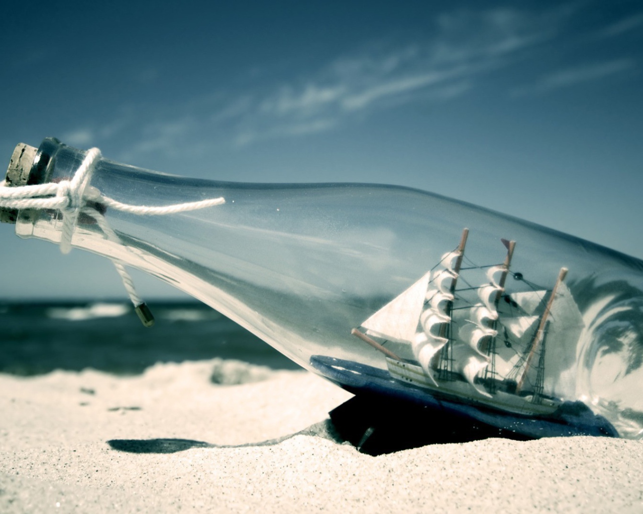 Фигурка корабля в бутылке на пляже