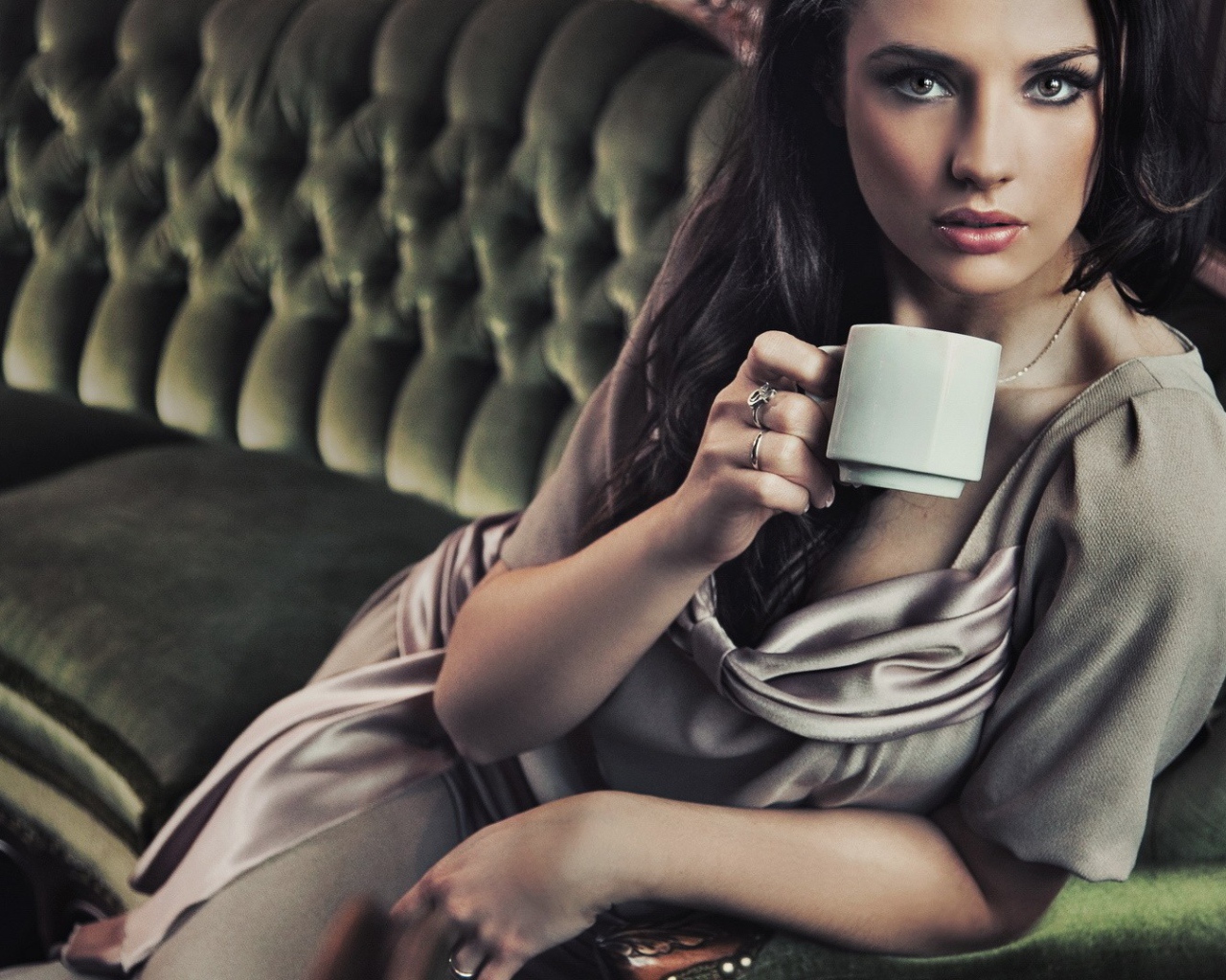 Brunette with a cup of coffee sitting on a sofa