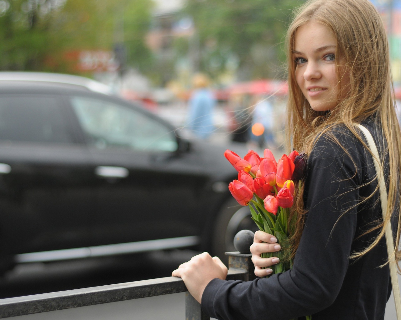 Девушка с букетом тюльпанов стоит у забора