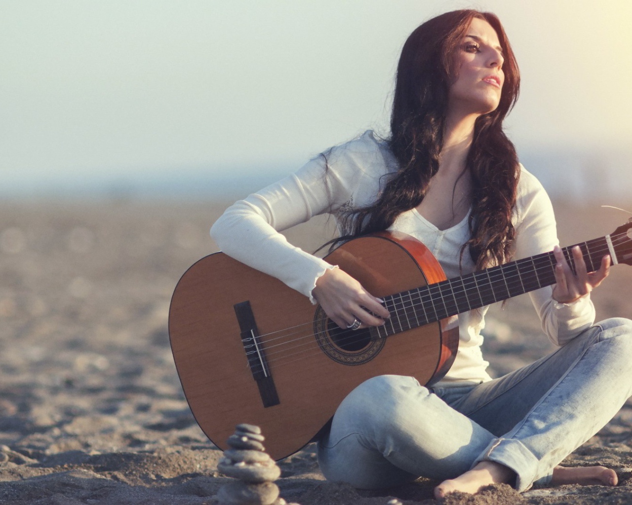 Греческая девушка сидит с гитарой на пляже