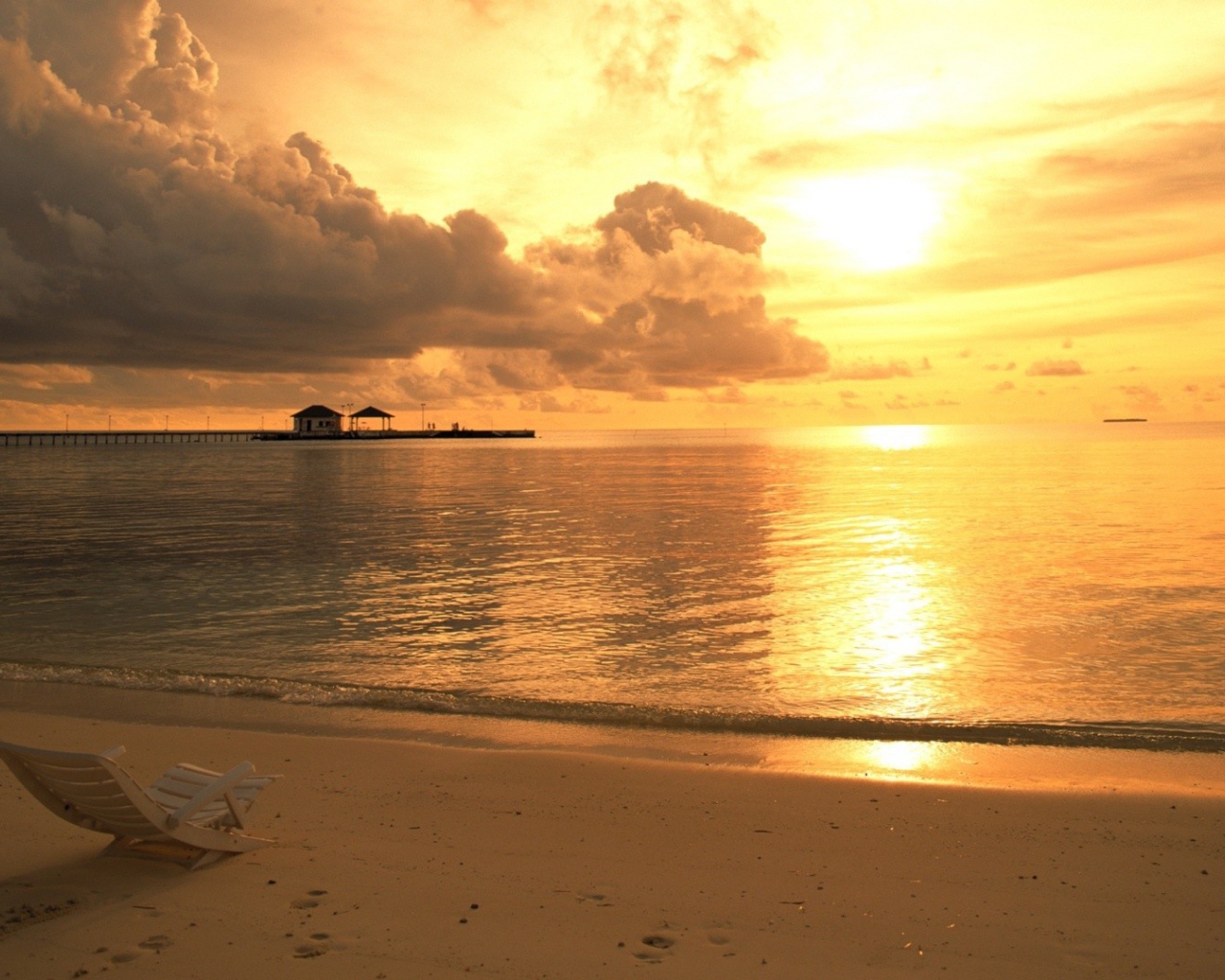 Одинокий шезлонг на пляже на закате