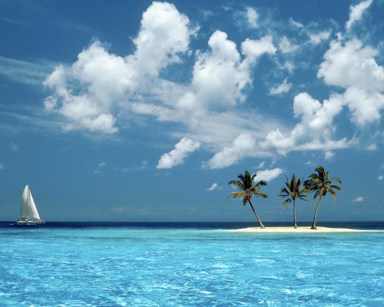 Парусник у песчаного острова с пальмами