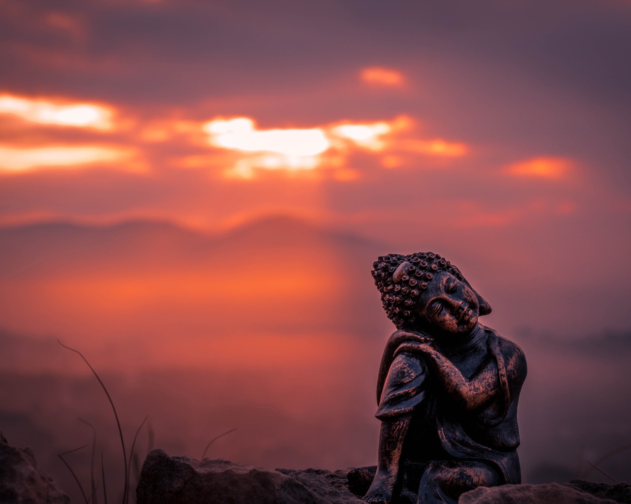 Статуя Будды на фоне солнца на закате