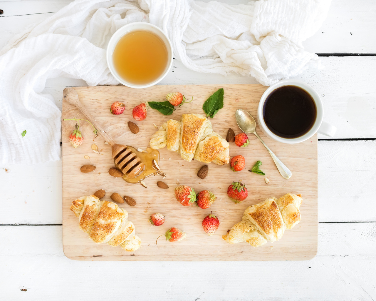 Круассаны, мед, свежие ягоды клубники и кофе на завтрак