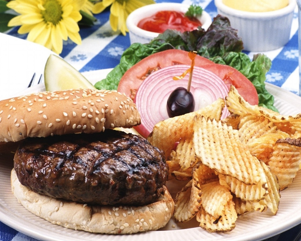 Гамбургер с котлетой и картофельные чипсы на тарелке с овощами