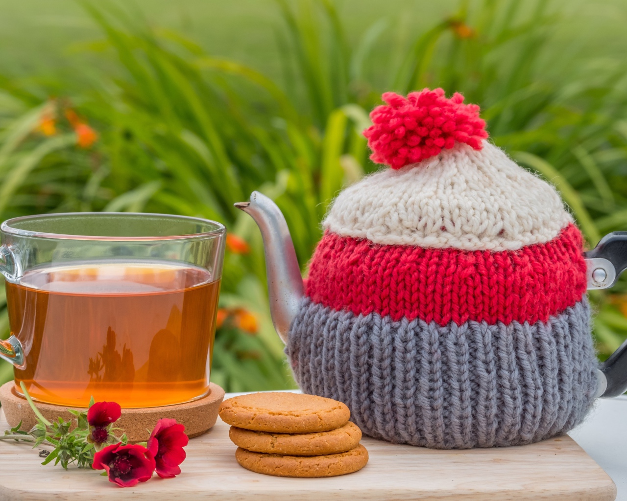 Чайник с чашкой чая на столе с печеньем и цветами