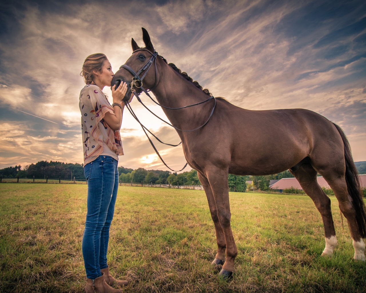 Красивая девушка целует коня под красивым небом
