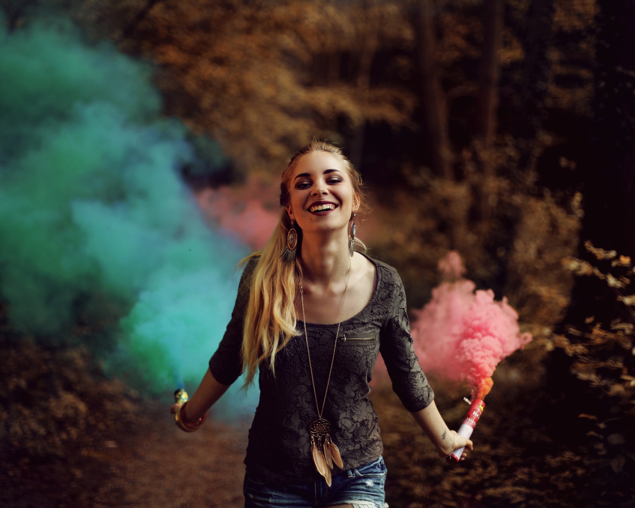 Красивая улыбающаяся девушка с дымовыми шашками в руках