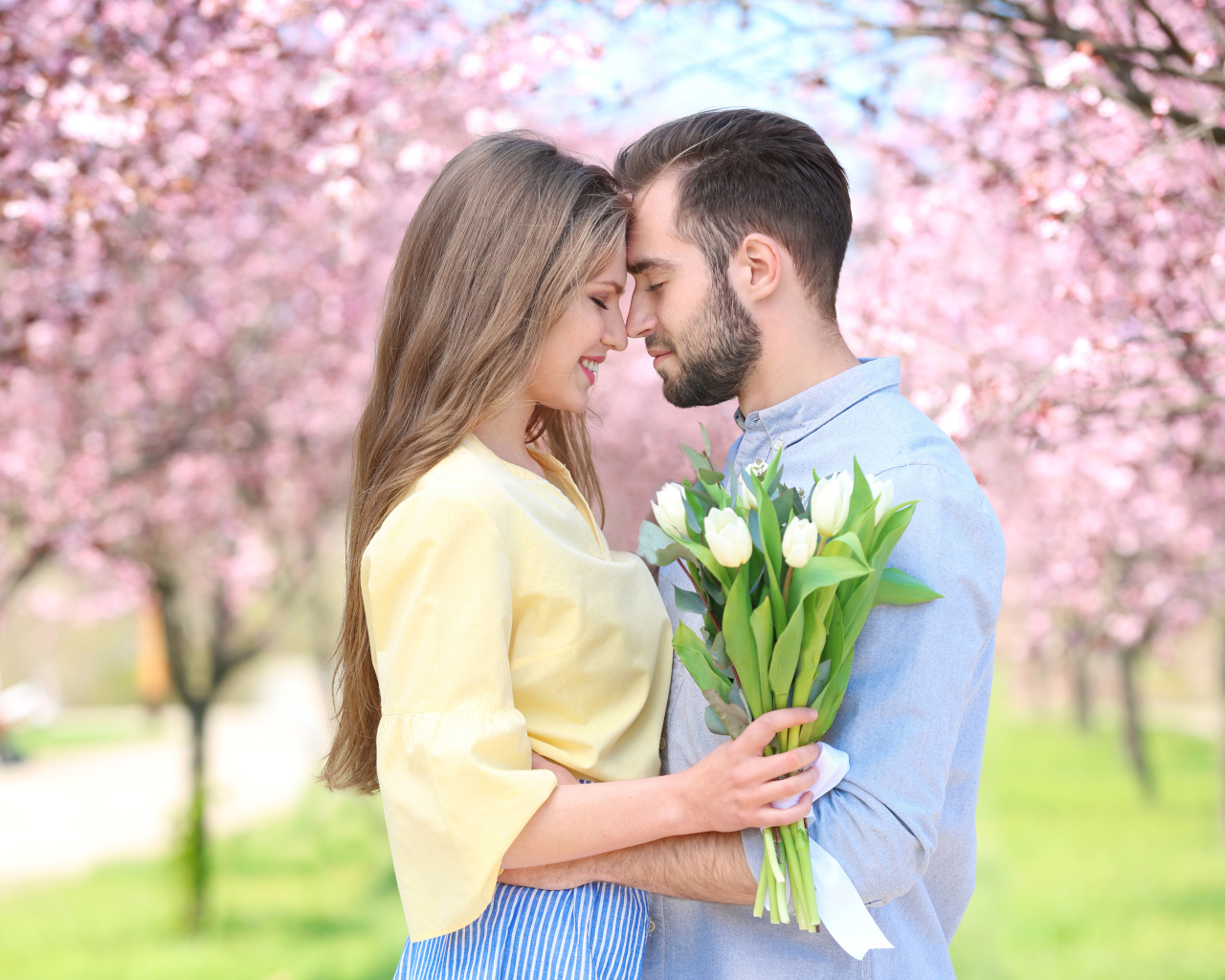 Влюбленная пара стоит в цветущем парке