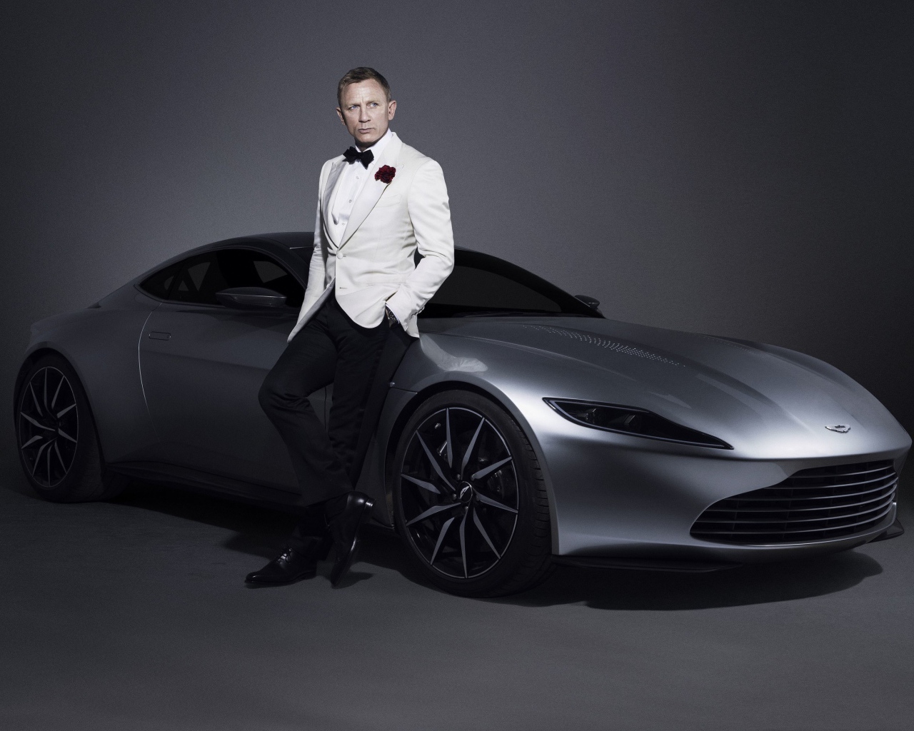 Знаменитый актер Дэниел Крэйг рядом с серебристым автомобилем Aston Martin