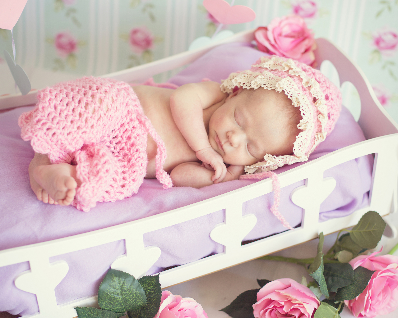 Спящий младенец девочка в розовом костюме в колыбели