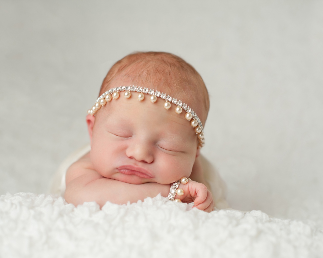 Маленький спящий грудной ребенок с красивым украшением на голове